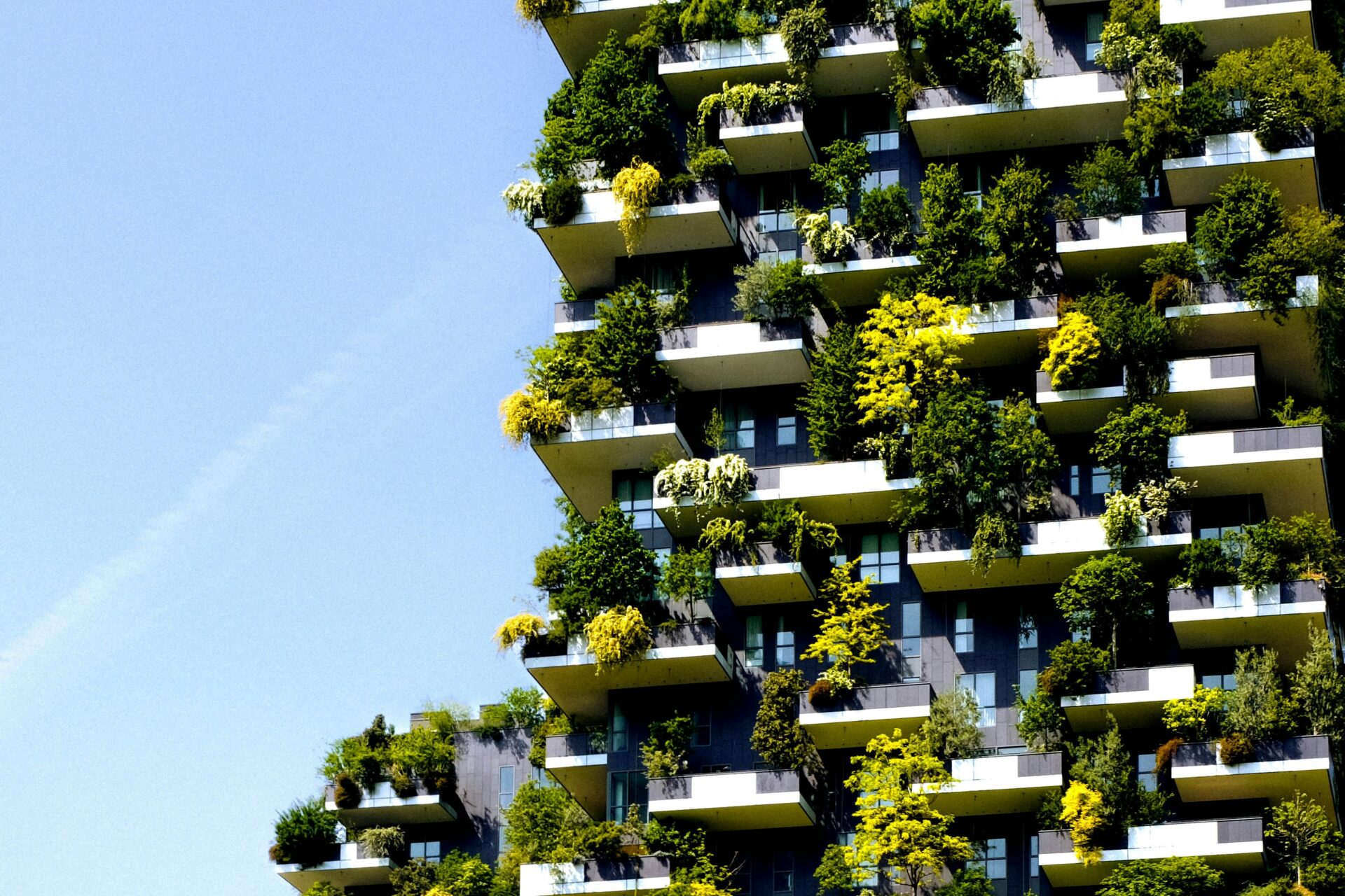 Edificio residencial con balcones llenos de árboles y vegetación. Arquitectura sostenible y estrategias ESG en el Real Estate impulsando la sostenibilidad.