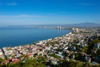 Panorámica de Puerto Vallarta, México, mostrando su costa y edificios. Análisis sobre la burbuja inmobiliaria en México. Vista aérea urbana.