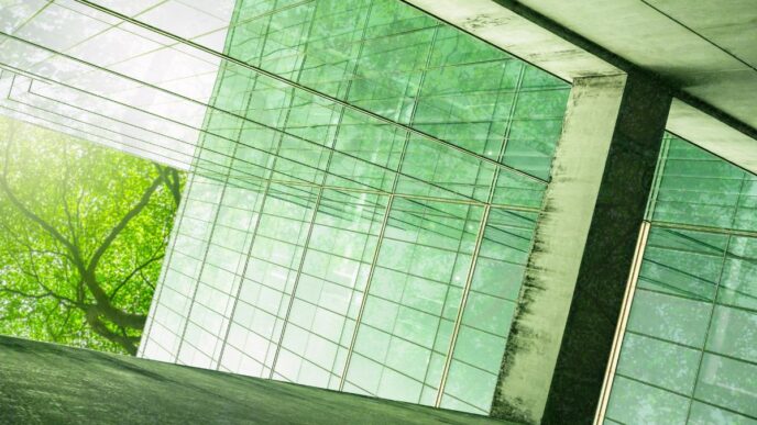 Edificio con fachada de cristal reflejando árboles, ejemplo de construcción sostenible en México. Diseño ecológico e innovador con luz natural.