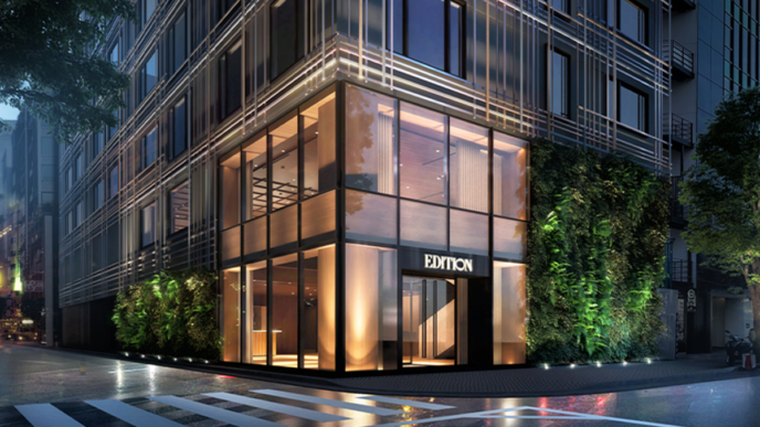 Fachada moderna del hotel de lujo EDITION, con vegetación vertical y amplios ventanales que reflejan la luz de la ciudad. Expansión de marcas hoteleras.