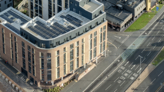 Vista aérea de edificio Build-to-Rent con paneles solares, reflejando la expansión de Starlight Investments en el mercado inmobiliario. Fachada moderna y vial.