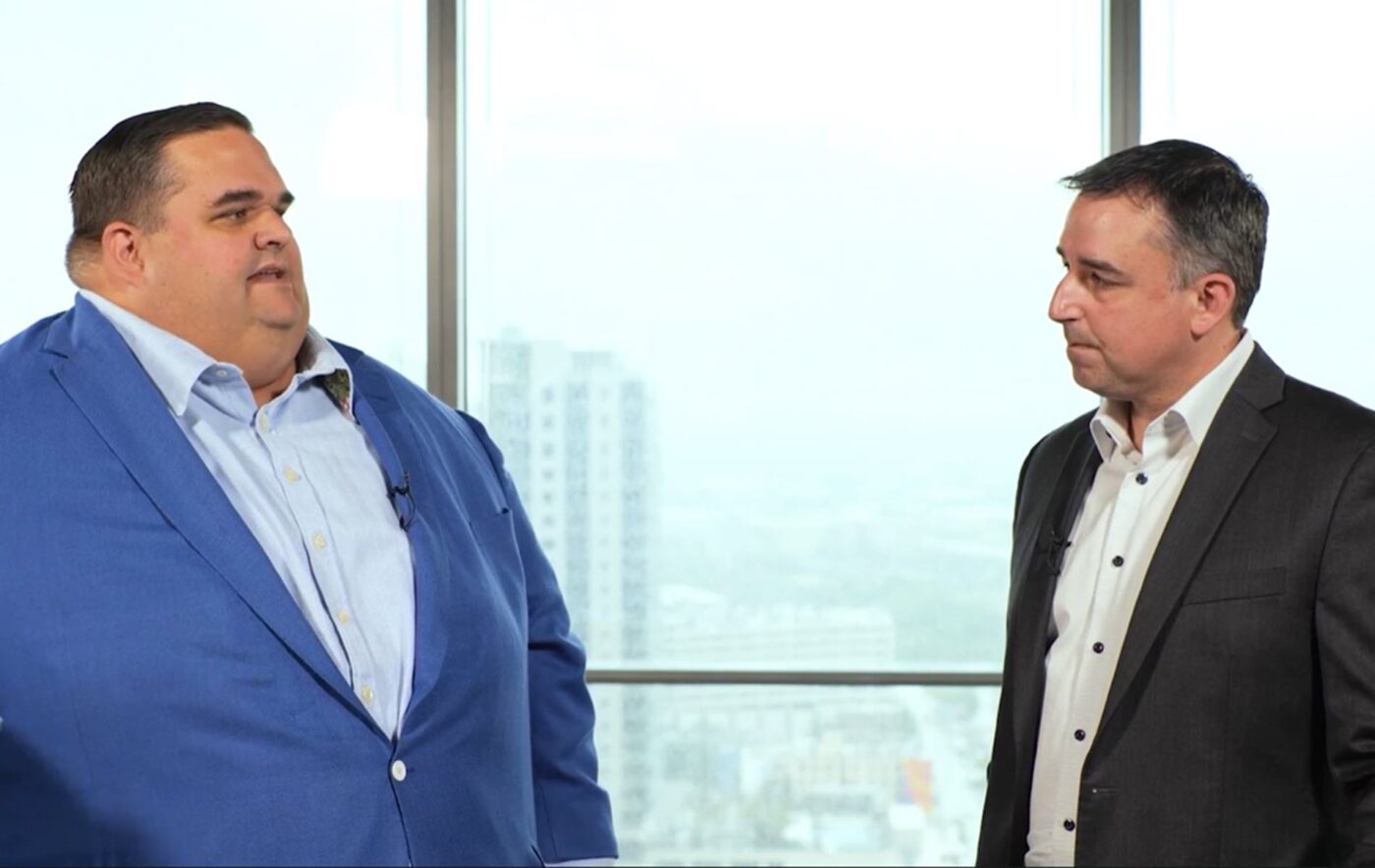 Dos hombres en traje discuten sobre liderazgo y sostenibilidad en EY, impulsando un futuro más verde y responsable. Compromiso global de EY.