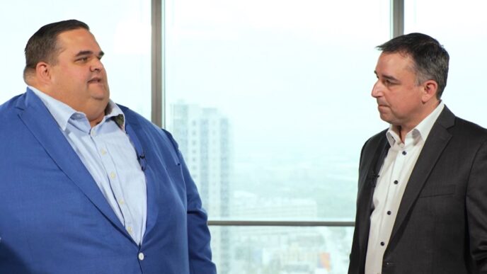 Dos hombres en traje discuten sobre liderazgo y sostenibilidad en EY, impulsando un futuro más verde y responsable. Compromiso global de EY.