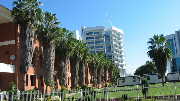 Fachada de inmueble con palmeras y edificios modernos. Fibra Danhos invierte en seguridad para proteger sus propiedades y garantizar la tranquilidad.