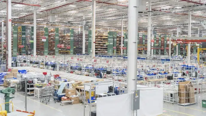 Vista interior de inmueble industrial de Fibra MTY, con estanterías altas y áreas de trabajo. Se visualiza la venta de un espacio de oficinas.