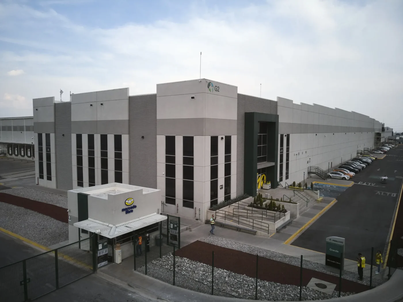 Edificio industrial de Fibra Uno, posible centro de Terrafina. Amplia estructura gris y blanca, vehículos estacionados. Perspectiva aérea.