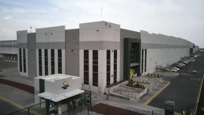 Edificio industrial de Fibra Uno, posible centro de Terrafina. Amplia estructura gris y blanca, vehículos estacionados. Perspectiva aérea.