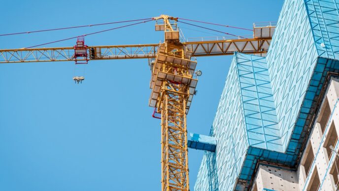 Grúa amarilla en obra de construcción con cielo azul. Ideal para financiamiento C-PACE en recapitalización inmobiliaria. Edificio en progreso.