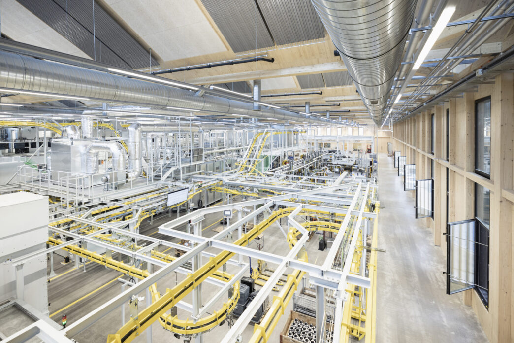 Vista aérea de planta industrial Metall Zug en Suiza, con maquinaria avanzada y sistemas de transporte. Impulso tecnológico visible en cada detalle.