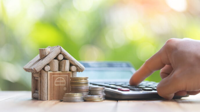 Financiamiento vivienda. Calculadora y casa de madera con monedas. Concepto de inversión inmobiliaria. Inmobiliare Summits LATAM.