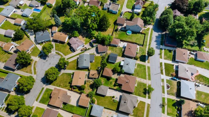 Vista aérea de viviendas sostenibles con finanzas verdes, MSquared. Casas con jardines, calles arboladas. Impulso a la vivienda eco-amigable.