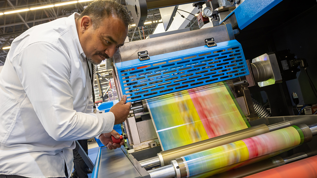 Networking/expo.

Visitante en la conferencia Inmobiliare Summits revisando una máquina de impresión durante un evento de real estate en México.