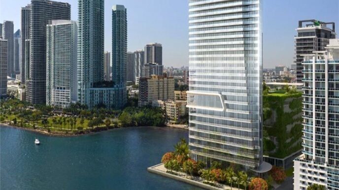 Vista del Edition Residences Miami Edgewater en Florida, torre moderna frente al mar con exuberante vegetación. Arquitectura innovadora y lujo en Edgewater.