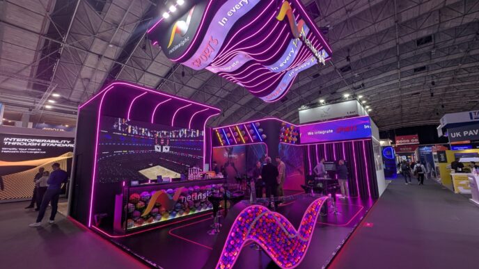 Stand en feria industrial con iluminación neón y logo Netinsight Sports. Diseño moderno e innovador para promoción de inmuebles industriales.