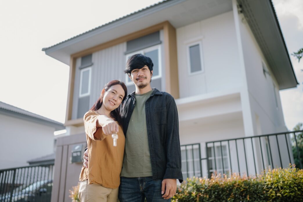 Real estate. Pareja sonriente muestra las llaves de su nueva casa. Inversión y felicidad en el sector inmobiliario.