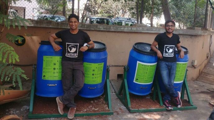 Dos personas junto a contenedores azules para gestión de residuos orgánicos. Solución sostenible para Real Estate con EarthSR. Compostaje eficiente.