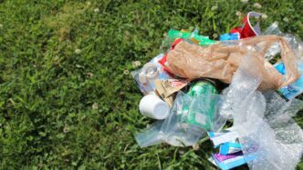 Montón de residuos mixtos en el césped, promoviendo la gestión sostenible de residuos en el sector inmobiliario y la concienciación ambiental.