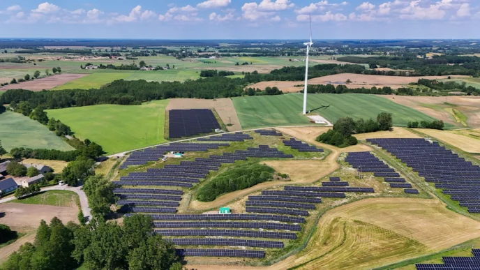 Vista aérea de central híbrida Greenvolt: paneles solares y aerogenerador en campo. Impulso a eficiencia energética y sostenibilidad ambiental.