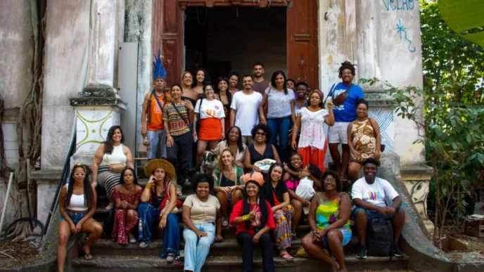 Grupo diverso frente a edificio antiguo. Operación de viviendas: Grupo Lar y Fondo Primonial en España. Gente sonriendo, ambiente comunitario, luz natural.