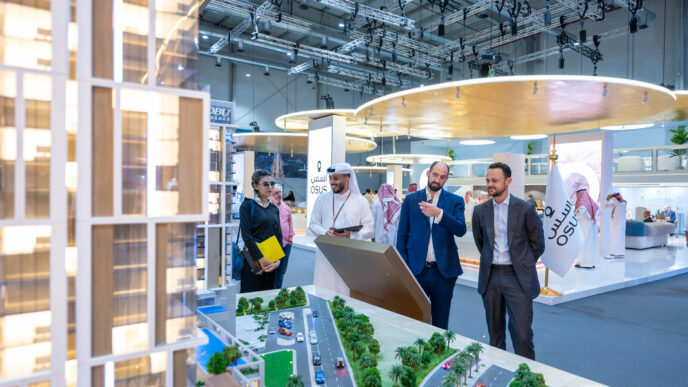 Networking en Inmobiliare Summits: asistentes examinan un modelo arquitectónico en el stand del patrocinador OSUS. Conferencia de real estate.