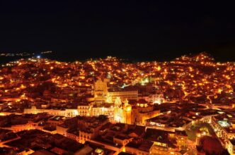 Vista nocturna de Guanajuato, México, con luces brillantes que iluminan la ciudad y resaltan la arquitectura histórica. Paisaje urbano cautivador.