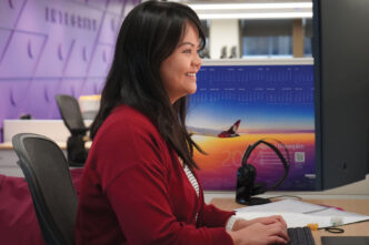 Mujer sonriente trabajando en oficina de Hemic Inversiones Inmobiliarias, crecimiento profesional y ambiente laboral productivo con equipo moderno.