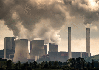 Vista de una nave industrial de Hershey's en construcción por Cemex, con chimeneas humeantes y cielos nublados, reflejando su impacto ambiental.
