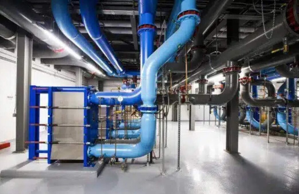 Compleja red de tuberías azules y grises, clave para el transporte de hidrógeno en un real estate sostenible. Avanzados sistemas de plomería.