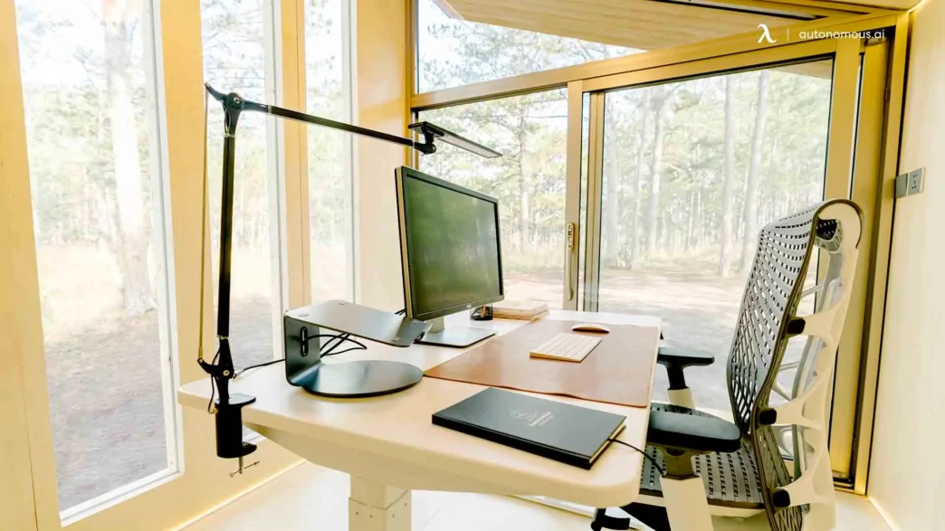 Oficina en casa con escritorio ajustable, monitor y silla ergonómica. Espacio de trabajo moderno y luminoso. Trabajo presencial vs home office.