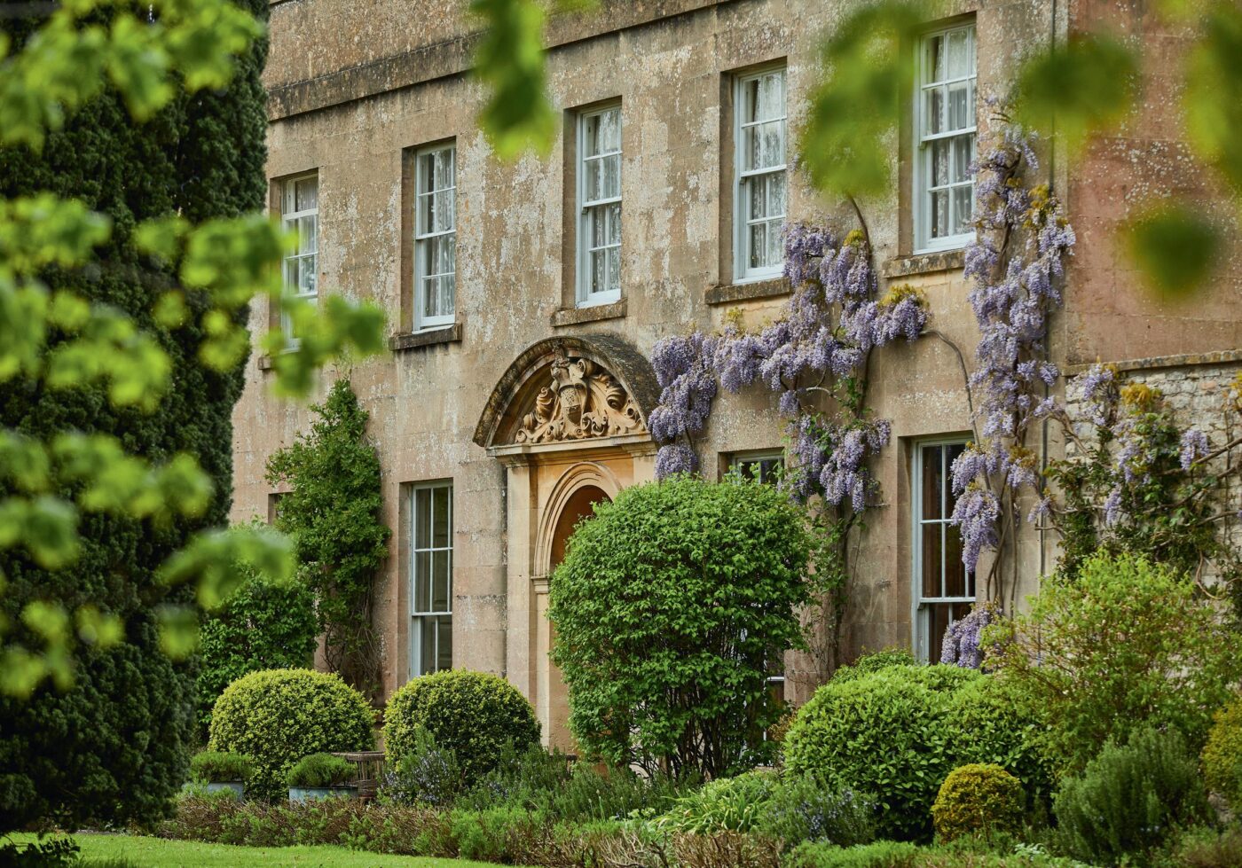 Fachada del Pilgrm Hotel, un hotel sostenible de estilo victoriano, con glicinas floreciendo y jardines exuberantes. El legado victoriano revive aquí.