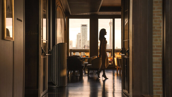 Arquitectura del venue en Inmobiliare Summits, México. Silueta de mujer camina frente a la ventana con vista a la ciudad en conferencia de real estate.