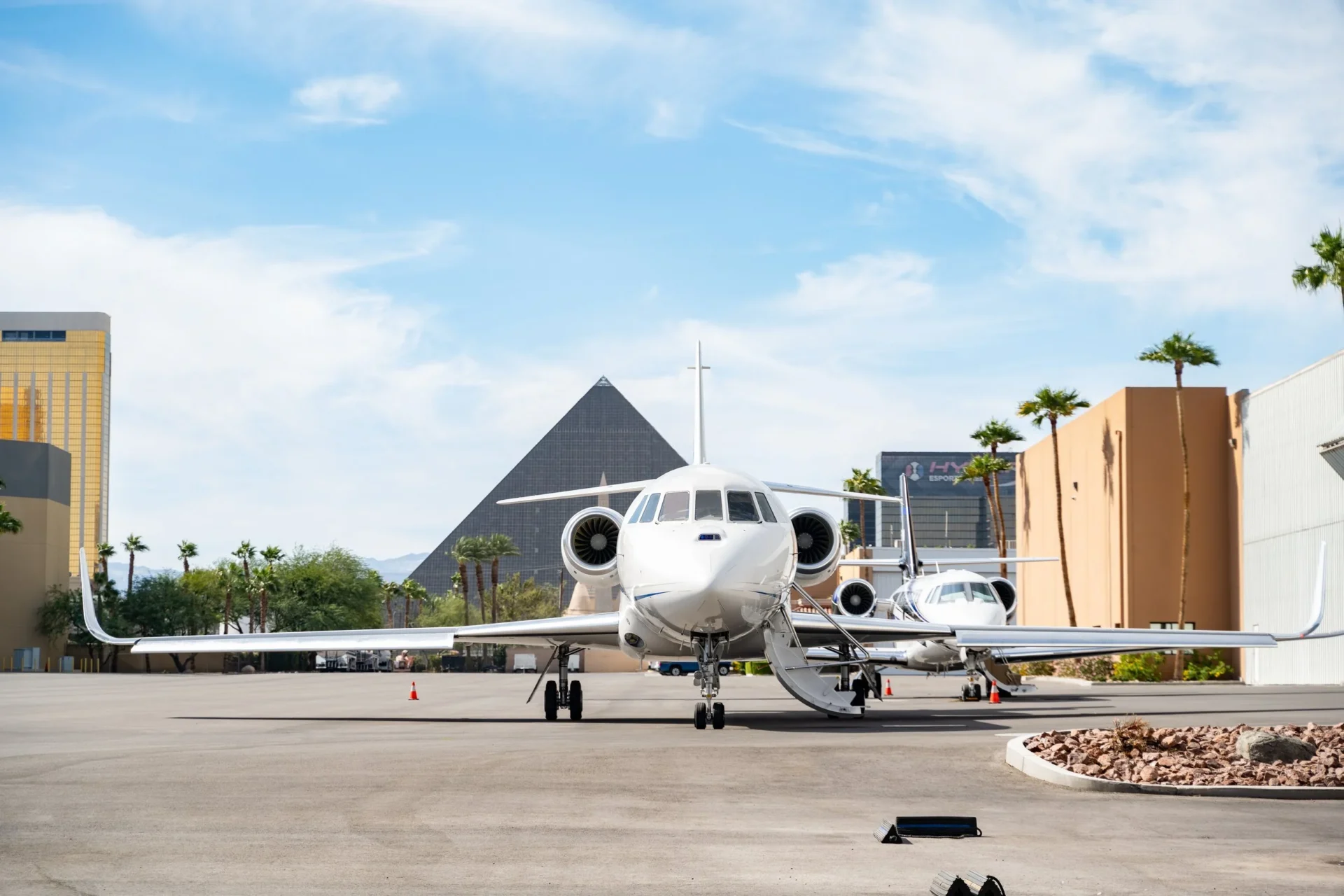 Imagen de un jet privado blanco estacionado en un hangar, con edificios emblemáticos de Las Vegas al fondo. Impacto adquisición hangar mercado inmobiliario