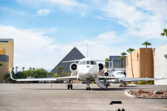 Imagen de un jet privado blanco estacionado en un hangar, con edificios emblemáticos de Las Vegas al fondo. Impacto adquisición hangar mercado inmobiliario