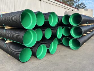 Montones de tuberías plásticas negras con interior verde. Impacto en la sostenibilidad inmobiliaria, esenciales para la gestión de aguas y residuos.