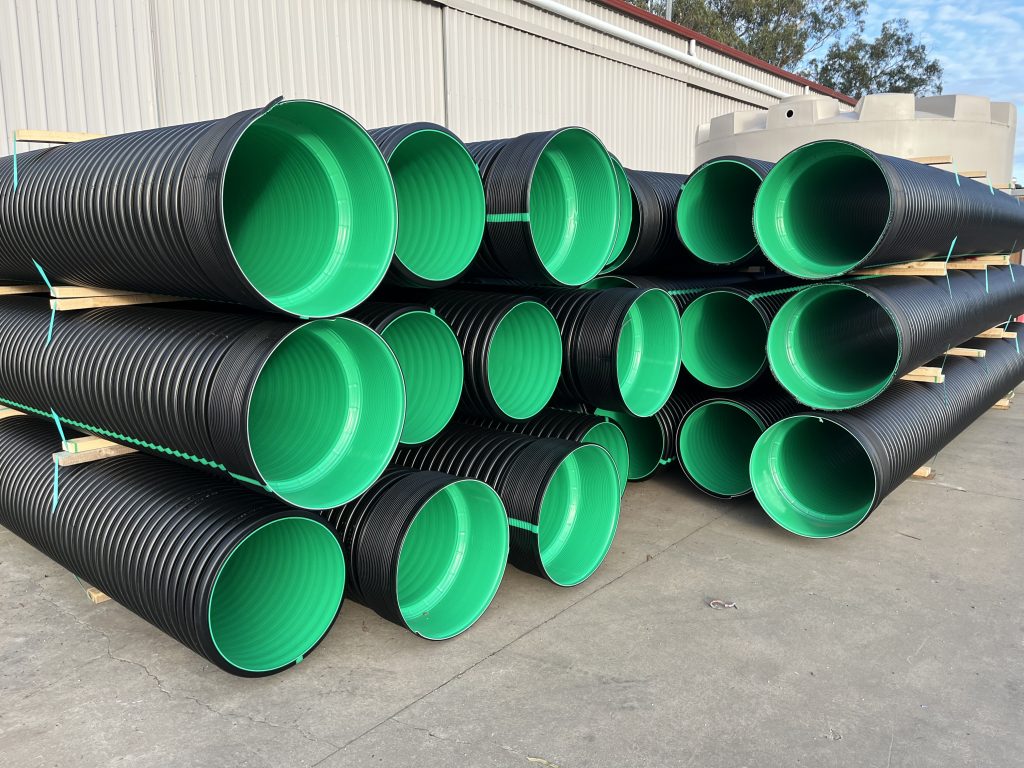 Montones de tuberías plásticas negras con interior verde. Impacto en la sostenibilidad inmobiliaria, esenciales para la gestión de aguas y residuos.