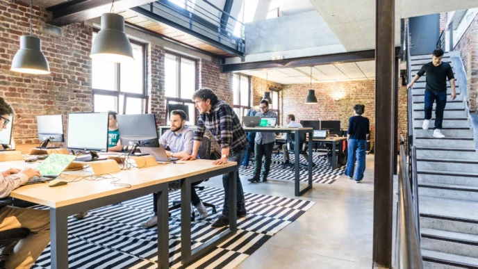 Espacio de trabajo moderno con gente en oficinas. Impacto del arrendamiento: diseño innovador para el mercado inmobiliario corporativo y coworking.