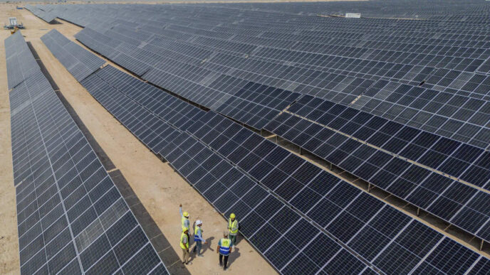 Vista aérea de un proyecto solar de 100 MW, mostrando paneles solares y un grupo de ingenieros. Energía solar e impacto inmobiliario reflejados.