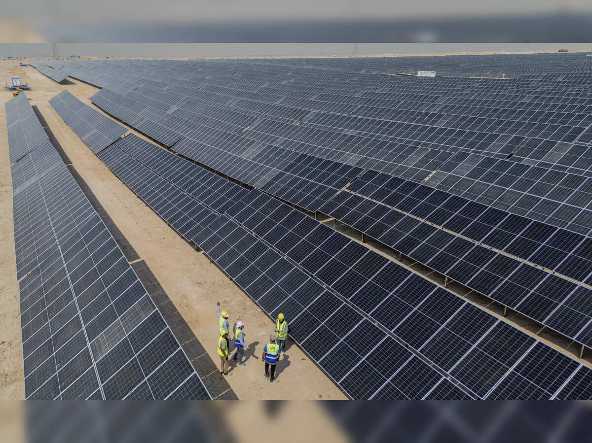 Vista aérea de un proyecto solar de 100 MW, mostrando paneles solares y un grupo de ingenieros. Energía solar e impacto inmobiliario reflejados.