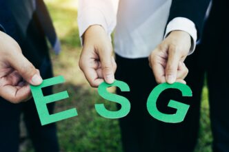 Personas sosteniendo letras verdes 'ESG'. Impacto Rating ESG en valor Real Estate. Concepto de inversión sostenible y responsabilidad ambiental.