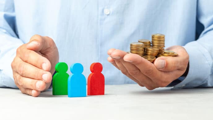 Conceptual. Inversión en México: Mano sostiene monedas junto a figuras que representan personas. Estrategias de inversión y desarrollo real estate.