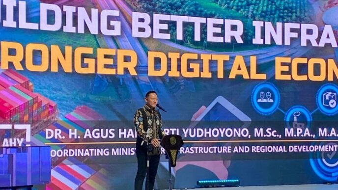 Indonesia impulsa infraestructura digital y talento: Hombre en pódium frente a pantalla con texto "Building Better Infra, Stronger Digital Econ"