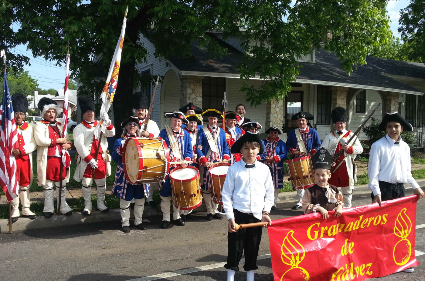 Desfile de los Granaderos de Gálvez en EE.UU. Músicos y participantes portan banderas. Evento cultural mexicano en la ciudad.
