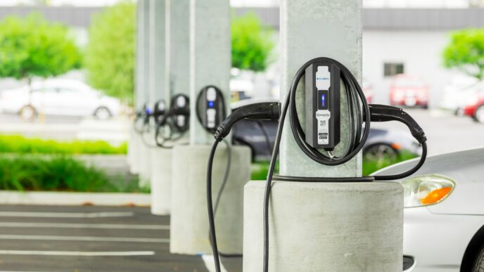 Infraestructura de carga eléctrica para vehículos en real estate, con estaciones alineadas y autos enchufados. Transformación sostenible visible.