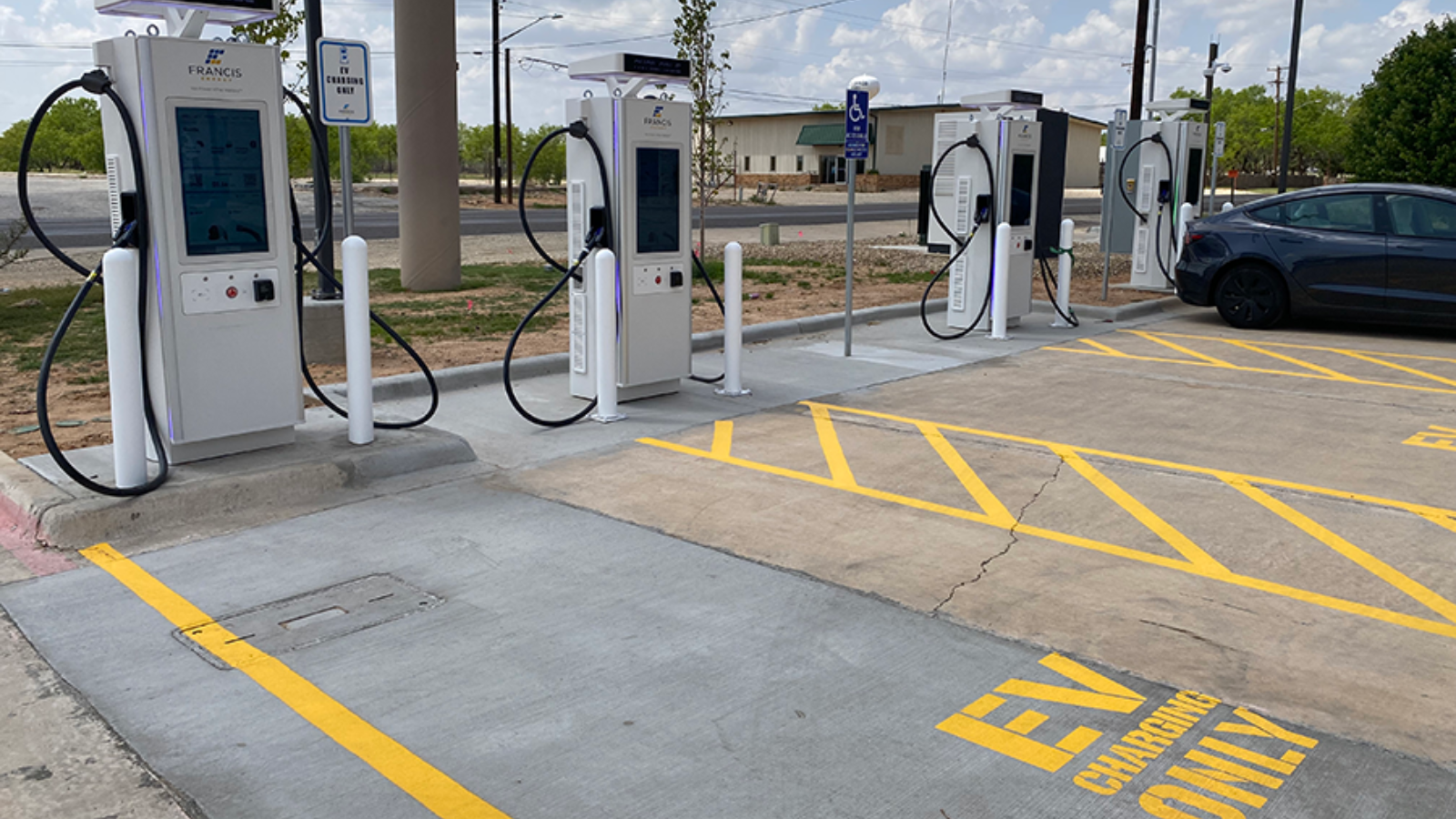 Estación de carga EV moderna con varios puntos, señalización clara y un coche eléctrico. Infraestructura clave para el Real Estate sostenible.