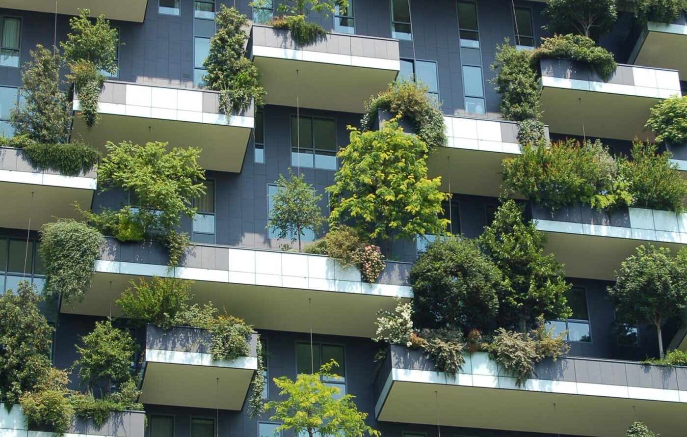 Fachada de edificio con balcones verdes que promueven iniciativas verdes y la eficiencia energética en edificios modernos. Diseño urbano sostenible.
