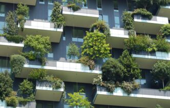 Fachada de edificio con balcones verdes que promueven iniciativas verdes y la eficiencia energética en edificios modernos. Diseño urbano sostenible.