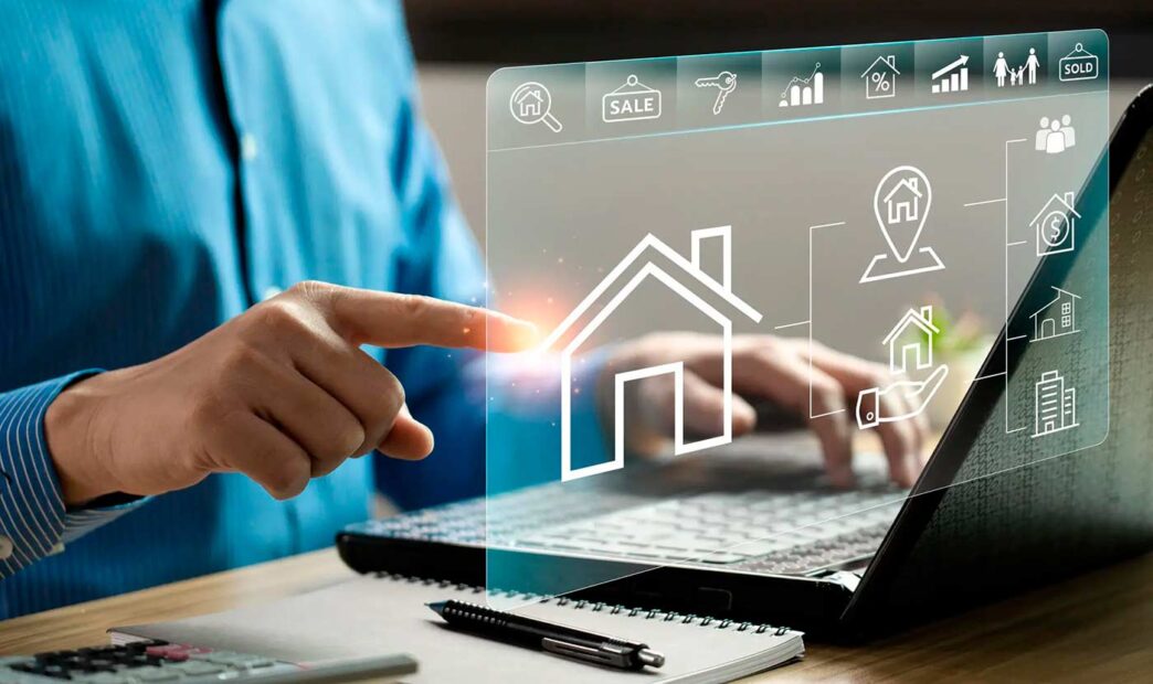Persona interactúa con laptop mostrando íconos de bienes raíces. Digitalización de trámites notariales en Inmobiliare Summits, México.