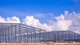 Estructura de acero en construcción bajo cielo azul, reflejando innovación en acero para construcciones sostenibles. Impulso a la construcción.