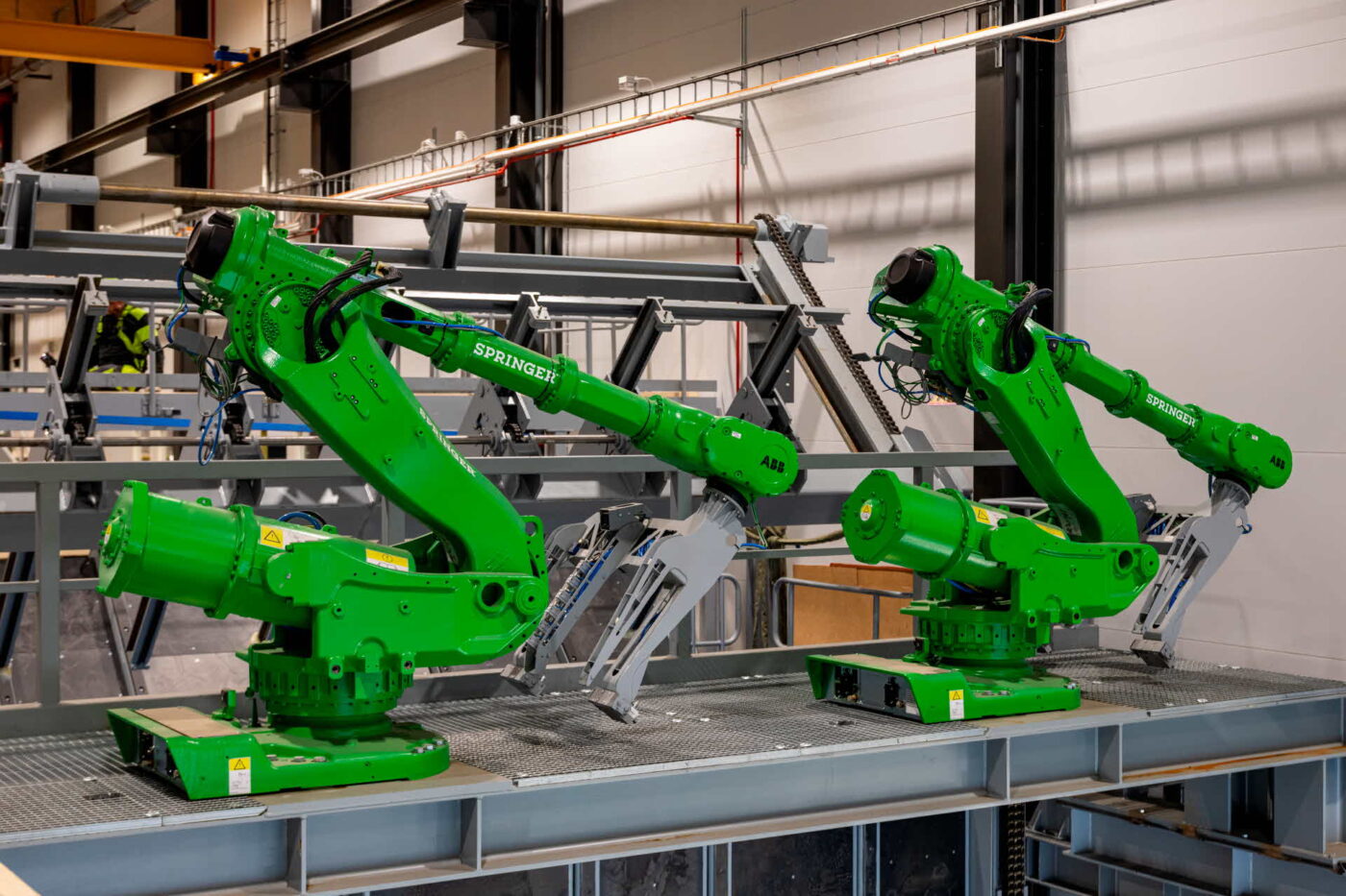 Dos robots verdes ABB Springer en aserradero inteligente. Automatización para innovación y sostenibilidad en la industria maderera moderna.