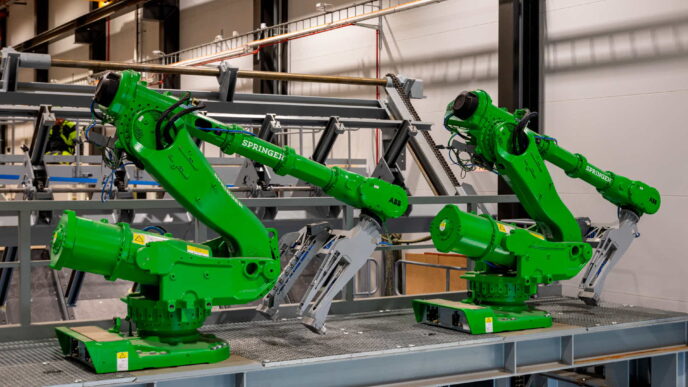 Dos robots verdes ABB Springer en aserradero inteligente. Automatización para innovación y sostenibilidad en la industria maderera moderna.